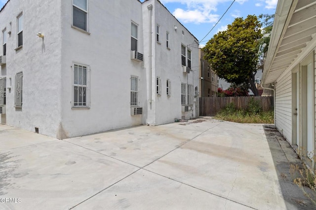 rear view of house featuring a patio, fence, and stucco siding