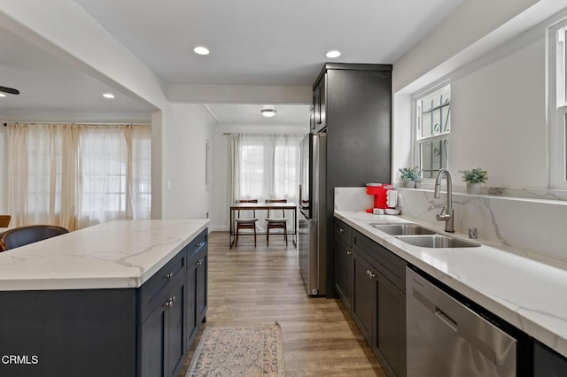 kitchen with light stone countertops, appliances with stainless steel finishes, a sink, light wood-style floors, and recessed lighting