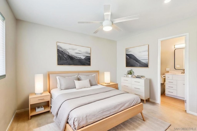 bedroom with connected bathroom, light hardwood / wood-style floors, sink, and ceiling fan