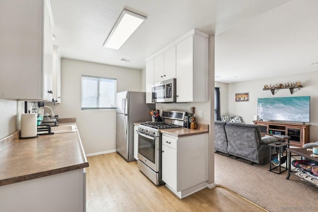 kitchen with white cabinetry, sink, light wood-type flooring, and appliances with stainless steel finishes