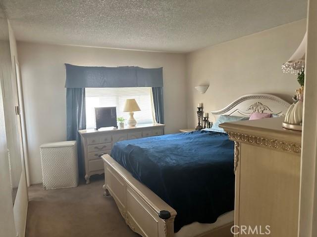 bedroom featuring light colored carpet and a textured ceiling