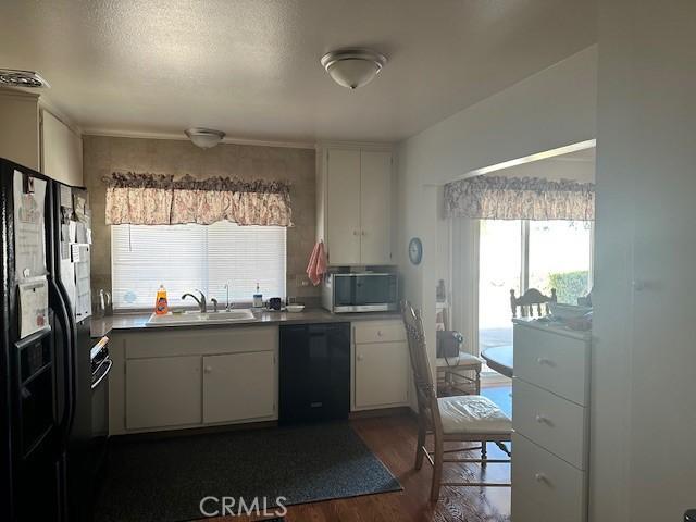 kitchen with black appliances, dark wood finished floors, white cabinets, a textured ceiling, and a sink