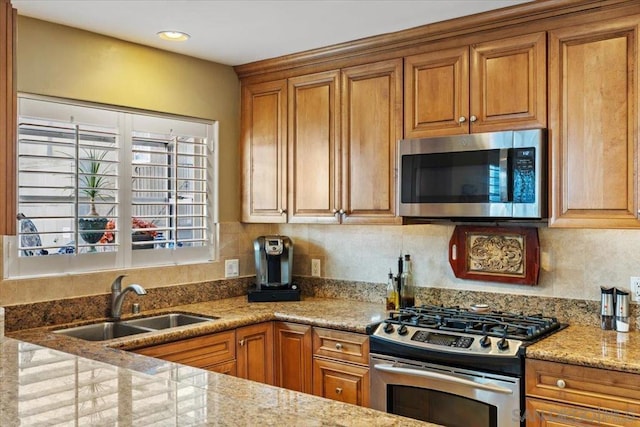 kitchen with light stone counters, sink, stainless steel appliances, and tasteful backsplash