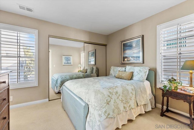 bedroom with a closet, light carpet, and multiple windows