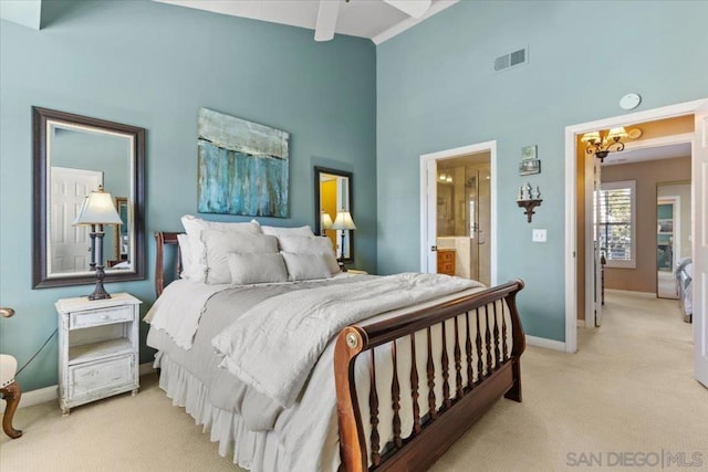 bedroom with light carpet, ceiling fan, ensuite bathroom, a towering ceiling, and beam ceiling