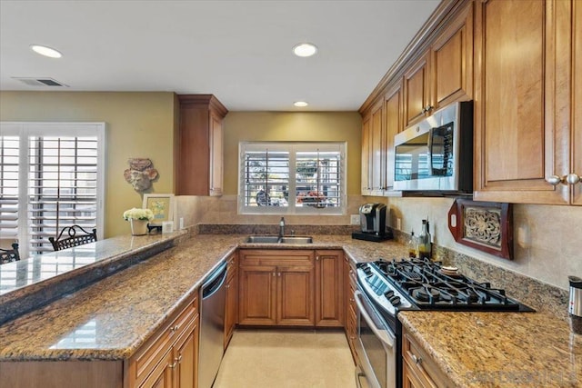 kitchen featuring stainless steel appliances, sink, kitchen peninsula, light tile patterned floors, and stone counters