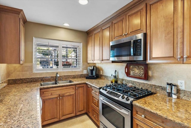 kitchen with light stone counters, sink, and appliances with stainless steel finishes