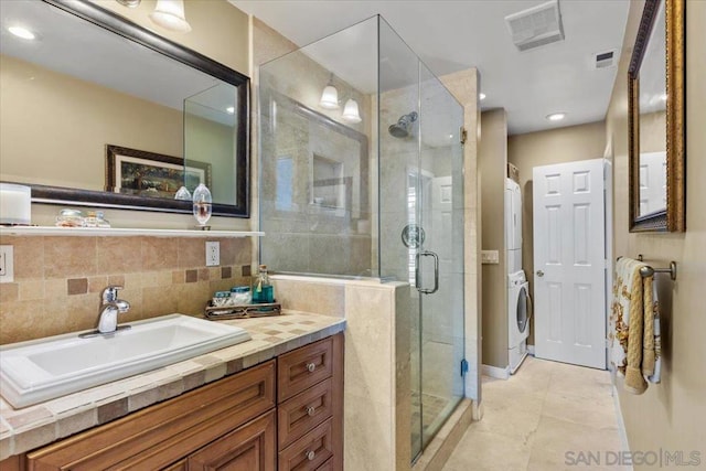 bathroom featuring an enclosed shower, tile patterned flooring, vanity, stacked washer and dryer, and decorative backsplash