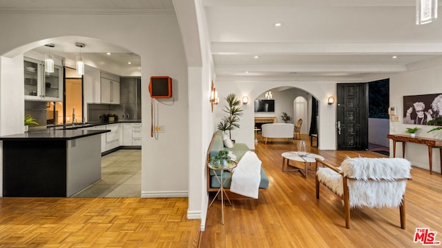 interior space featuring white cabinets, crown molding, hanging light fixtures, refrigerator, and beam ceiling