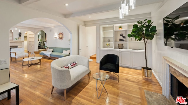 living room featuring a fireplace, light hardwood / wood-style flooring, and beam ceiling