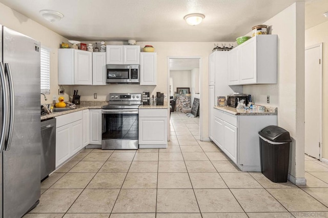 kitchen with sink, white cabinetry, light tile patterned floors, and appliances with stainless steel finishes