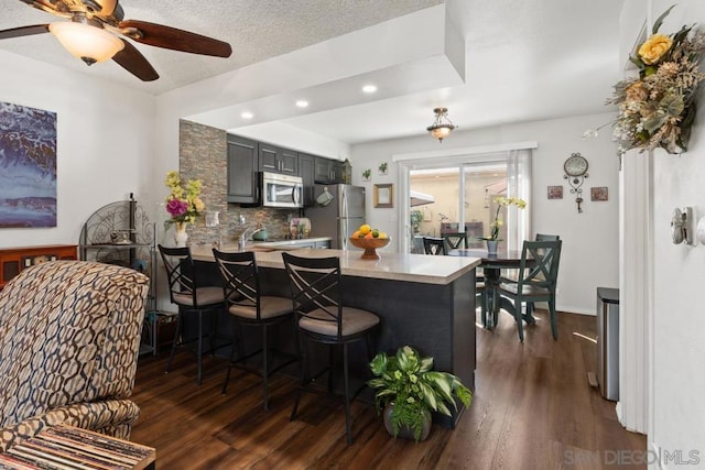 kitchen featuring stainless steel appliances, kitchen peninsula, dark hardwood / wood-style floors, and a breakfast bar