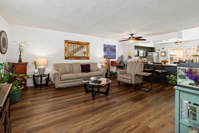 living room with a textured ceiling, dark hardwood / wood-style floors, and ceiling fan