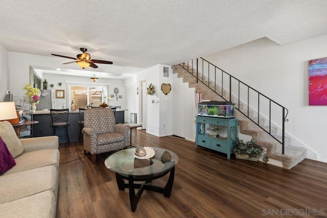 living room with a textured ceiling, dark hardwood / wood-style floors, and ceiling fan