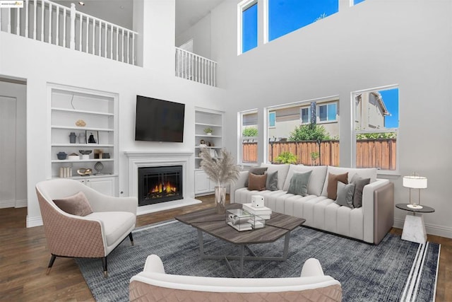 living room with built in features, dark hardwood / wood-style floors, and a high ceiling