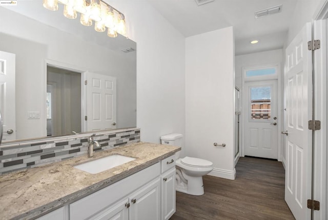 bathroom featuring wood-type flooring, toilet, vanity, and tasteful backsplash