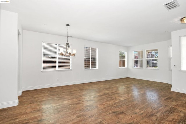 spare room with an inviting chandelier and dark wood-type flooring