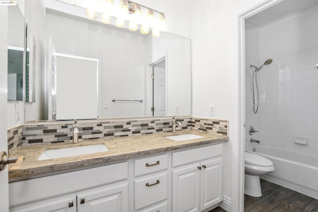 full bathroom with toilet, tasteful backsplash, tiled shower / bath combo, hardwood / wood-style flooring, and vanity