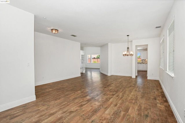 empty room featuring dark hardwood / wood-style flooring and an inviting chandelier