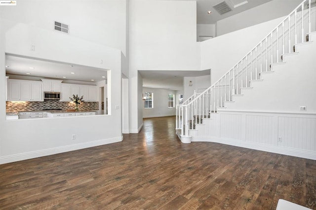 foyer entrance featuring a towering ceiling and dark wood-type flooring