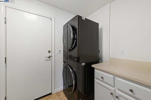 laundry room featuring stacked washer and clothes dryer, light tile patterned floors, and cabinets