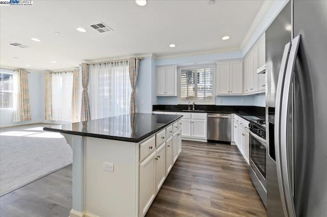 kitchen with white cabinets, a center island, appliances with stainless steel finishes, and sink