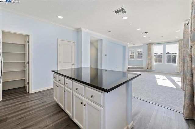 kitchen with a kitchen island, white cabinets, dark hardwood / wood-style floors, and ornamental molding