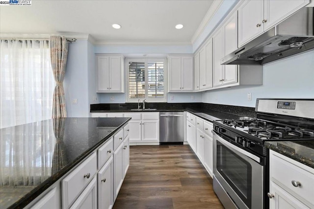 kitchen with crown molding, dark wood-type flooring, white cabinetry, dark stone counters, and stainless steel appliances