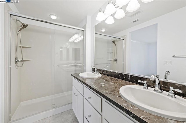 bathroom with a shower with shower door, tile patterned floors, and vanity