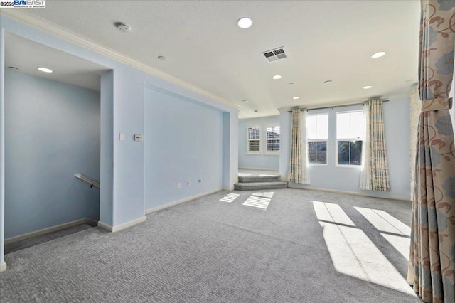 unfurnished living room featuring light colored carpet and ornamental molding