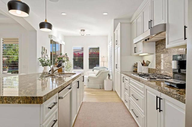 kitchen with hanging light fixtures, white cabinetry, and sink