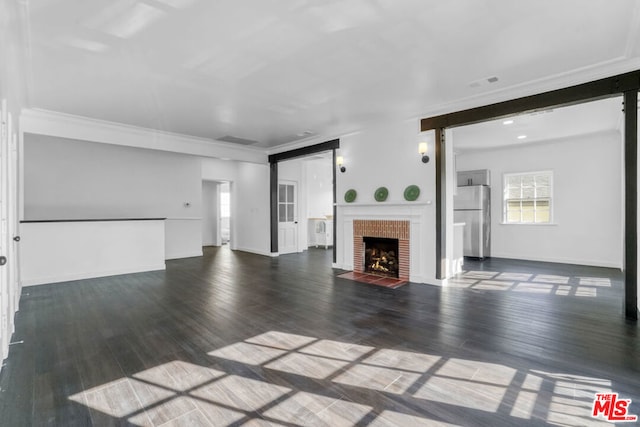 unfurnished living room featuring a fireplace, dark wood-type flooring, and crown molding