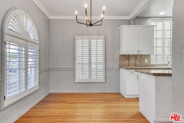 kitchen with light wood-type flooring, white cabinetry, tasteful backsplash, dark stone counters, and ornamental molding