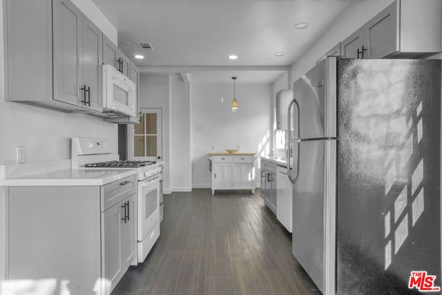 kitchen with pendant lighting, white appliances, gray cabinetry, and dark hardwood / wood-style flooring