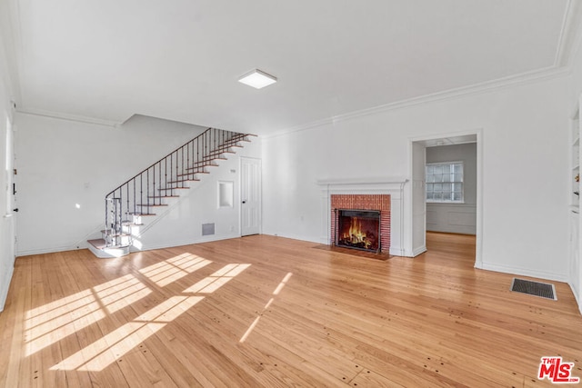 unfurnished living room with a brick fireplace, crown molding, and wood-type flooring