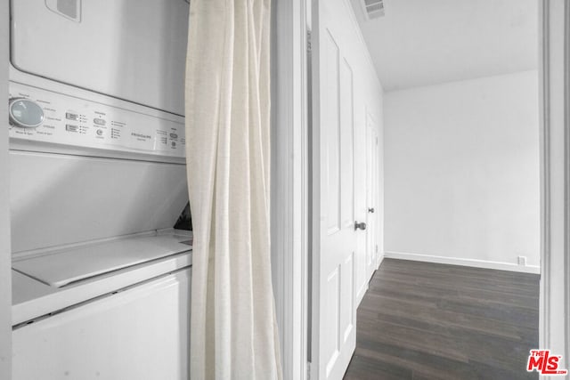 clothes washing area featuring stacked washer / dryer and dark wood-type flooring