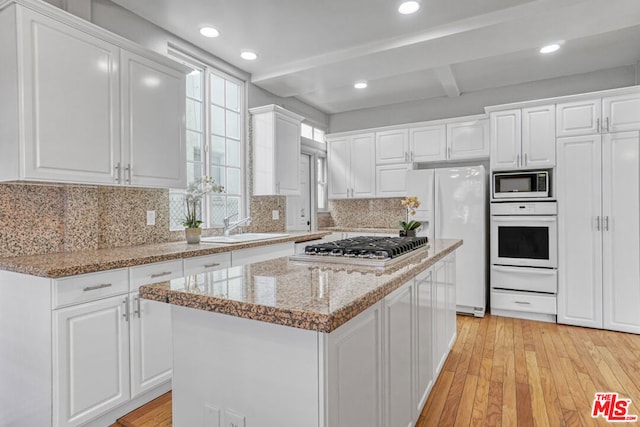 kitchen with white cabinets, a kitchen island, and white appliances