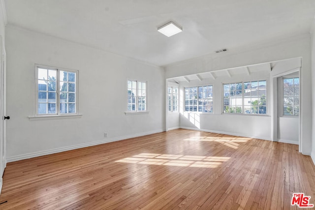 empty room with ornamental molding and light hardwood / wood-style floors