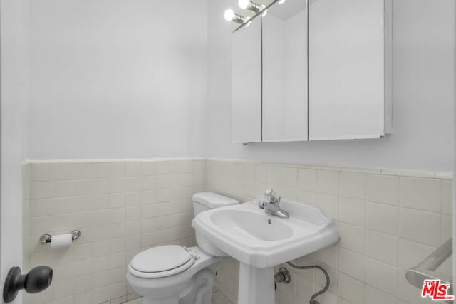 bathroom featuring tile walls and toilet