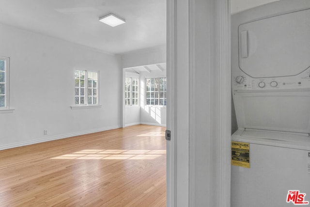 laundry area with stacked washer and clothes dryer and light hardwood / wood-style floors