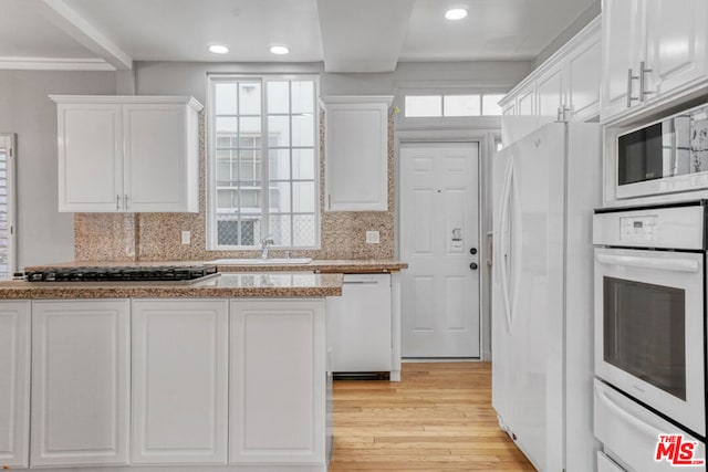 kitchen featuring white appliances, decorative backsplash, light wood-type flooring, and white cabinets