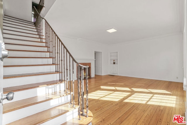 staircase featuring hardwood / wood-style floors and ornamental molding