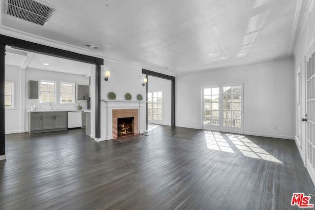 unfurnished living room featuring a fireplace, sink, dark hardwood / wood-style floors, and ornamental molding