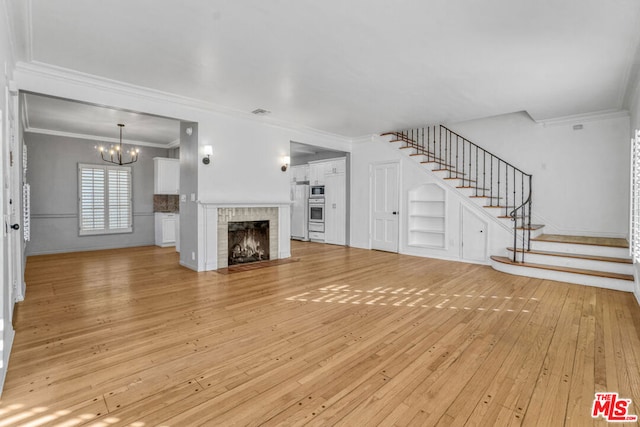 unfurnished living room featuring a fireplace, built in features, light hardwood / wood-style floors, and ornamental molding