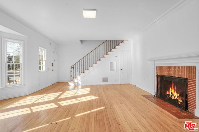 unfurnished living room with a fireplace, wood-type flooring, and crown molding