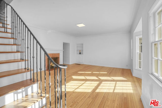 interior space with built in features, crown molding, a fireplace, and wood-type flooring