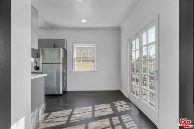 kitchen featuring a healthy amount of sunlight, dark hardwood / wood-style flooring, stainless steel fridge, and ornamental molding