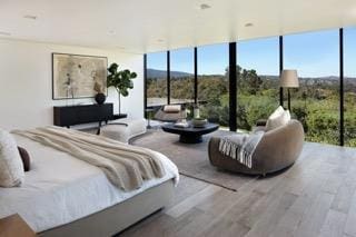 bedroom with expansive windows and wood-type flooring