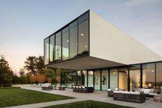 back house at dusk featuring an outdoor living space, a patio area, and a lawn