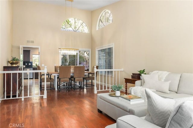 living room with dark wood-type flooring and a towering ceiling